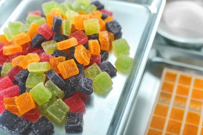 square gummies in a pile that are purple, orange, red, and green