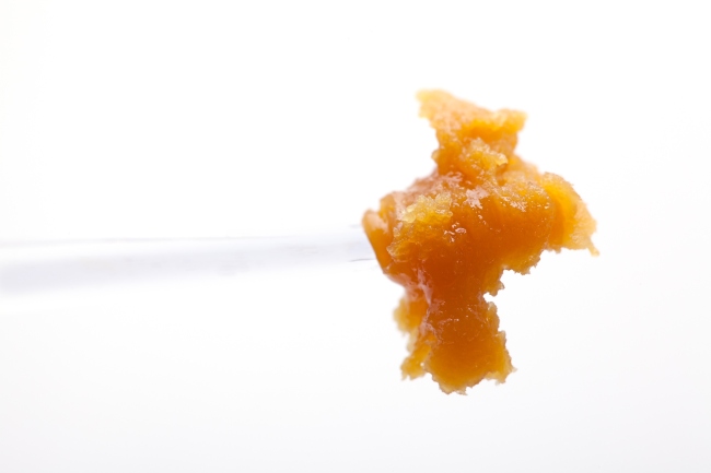a chuck of orange cannabis wax that is on the tip of a dab tool