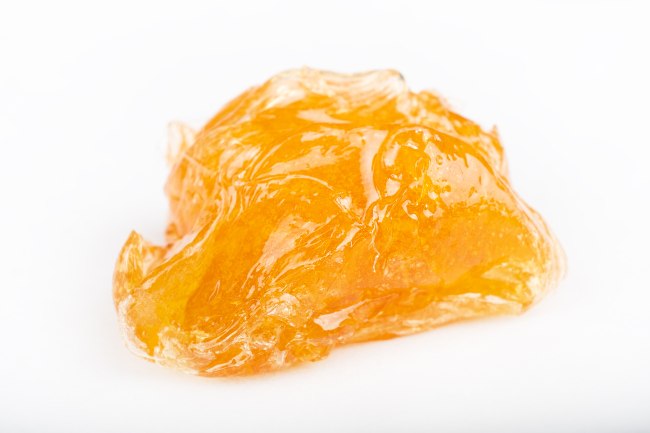 a large chunk of sticky yellowish orange cannabis wax on a white background