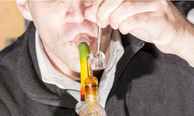 a man taking a dab from a colorful rig