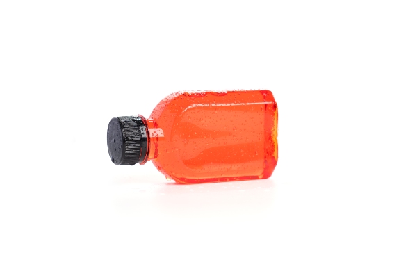 A plastic bottle lying on its side with red liquid inside