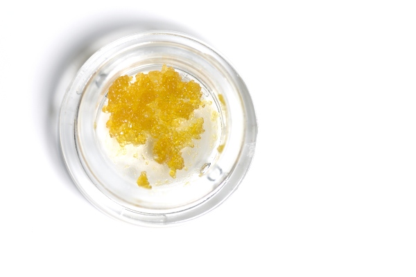 A clear jar with yellow cannabis substance inside
