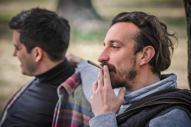 Two men smoking a cannabis joint in the park 
