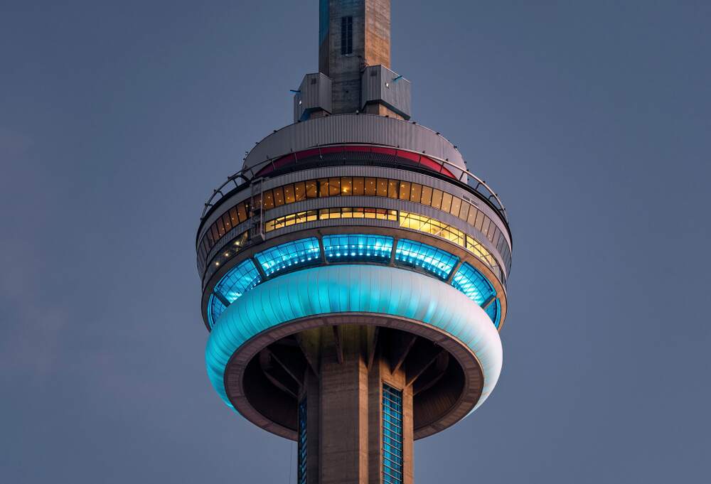 Close-up of the CN Tower lit up in bright blue at dusk in Toronto, Ontario, Canada.